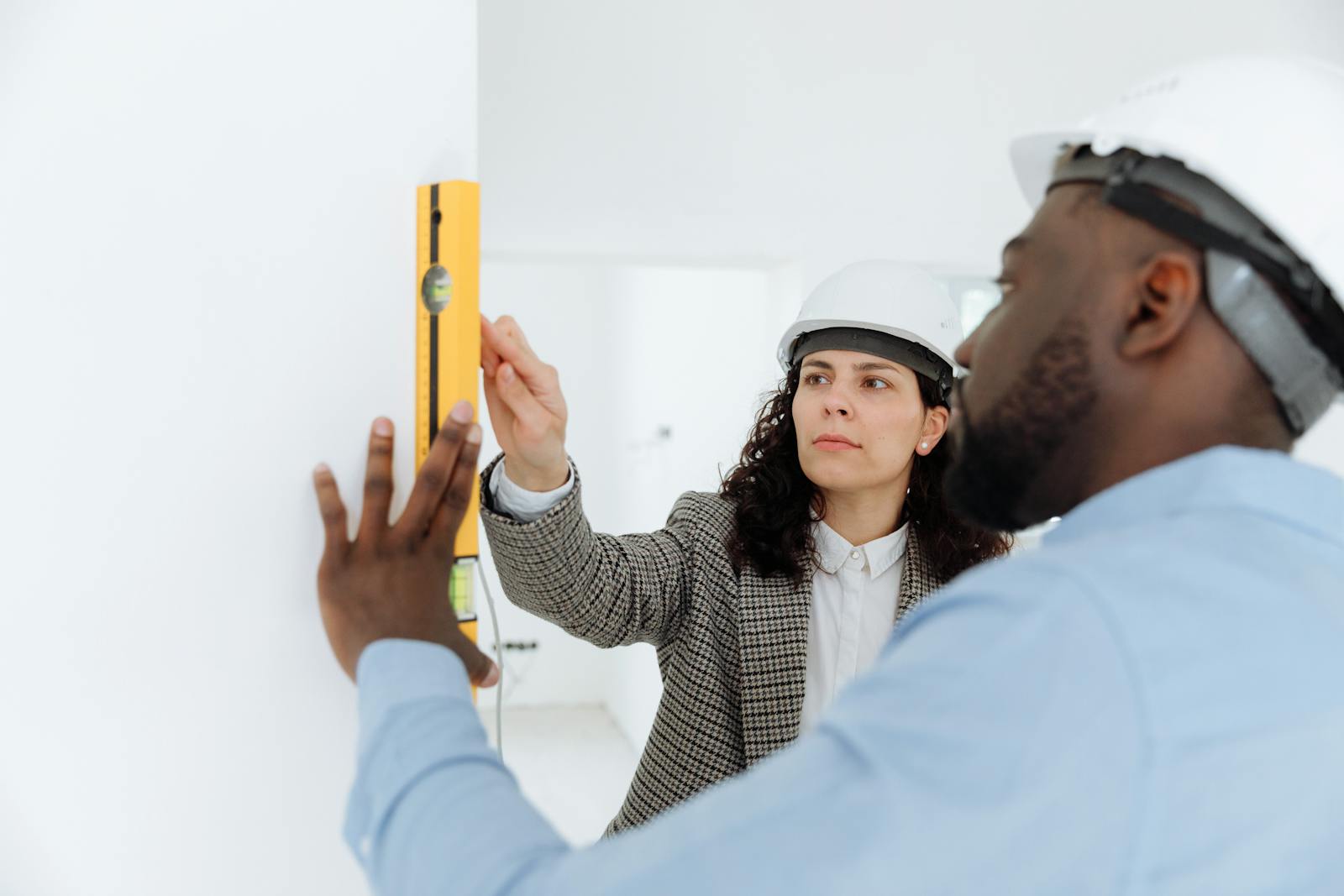 Man and Woman Checking a Level Bar on a Wall, contractors